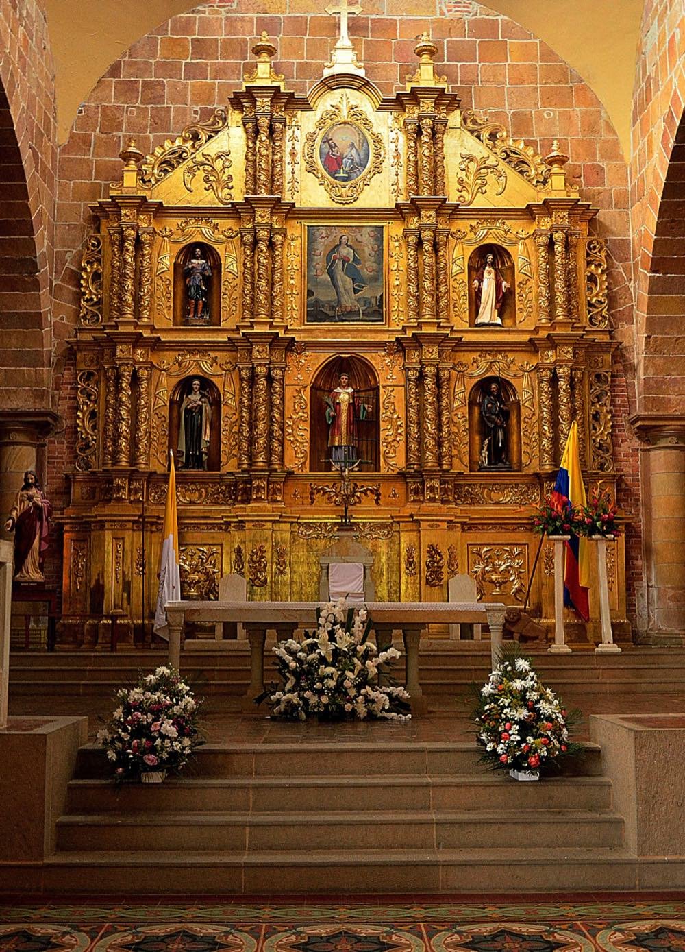 Altar mayor dorado y tallado del interior de la catedral de Barichara, con arreglos florales en las escalinatas