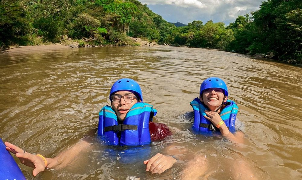 Dos turistas con casco y chaleco salvavidas flotando en las aguas del río Fonce durante un recorrido de canotaje