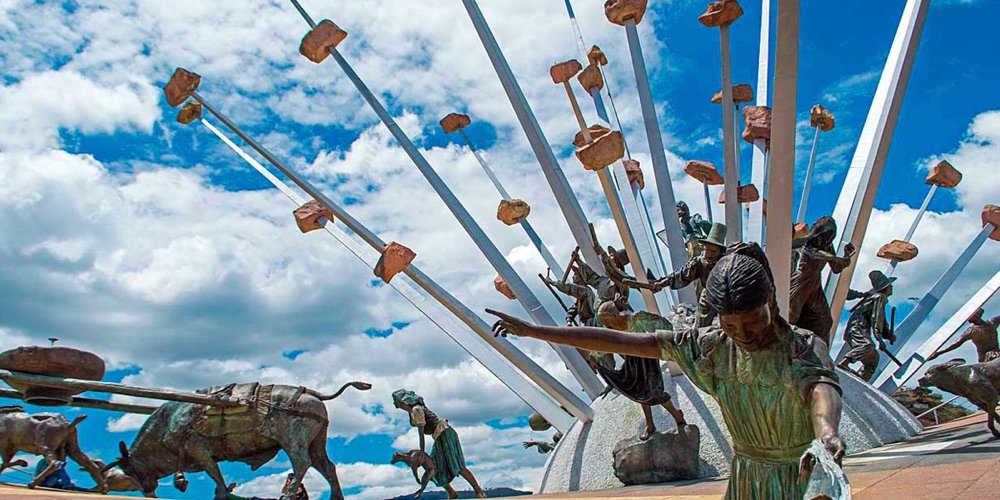Detalle de las esculturas de bronce del Monumento a la Independencia en el cañón del Chicamocha, con nubes de fondo