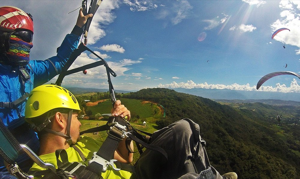 Vista en pleno vuelo desde un parapente tándem sobre el valle de Curití, con otros parapentes en el aire alrededor