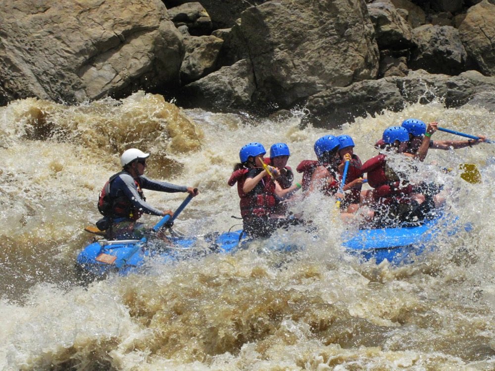 Balsa de rafting nivel V atravesando un rápido embravecido y ancho del río Suárez entre rocas grandes