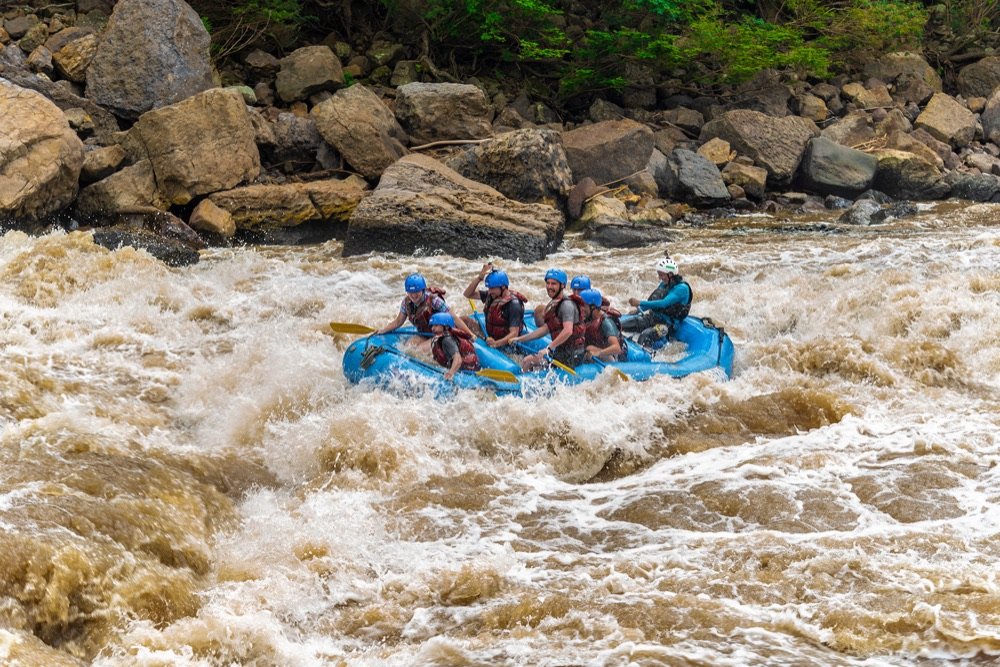 Varias balsas de rafting avanzando en fila por un rápido grande y turbulento del río Suárez